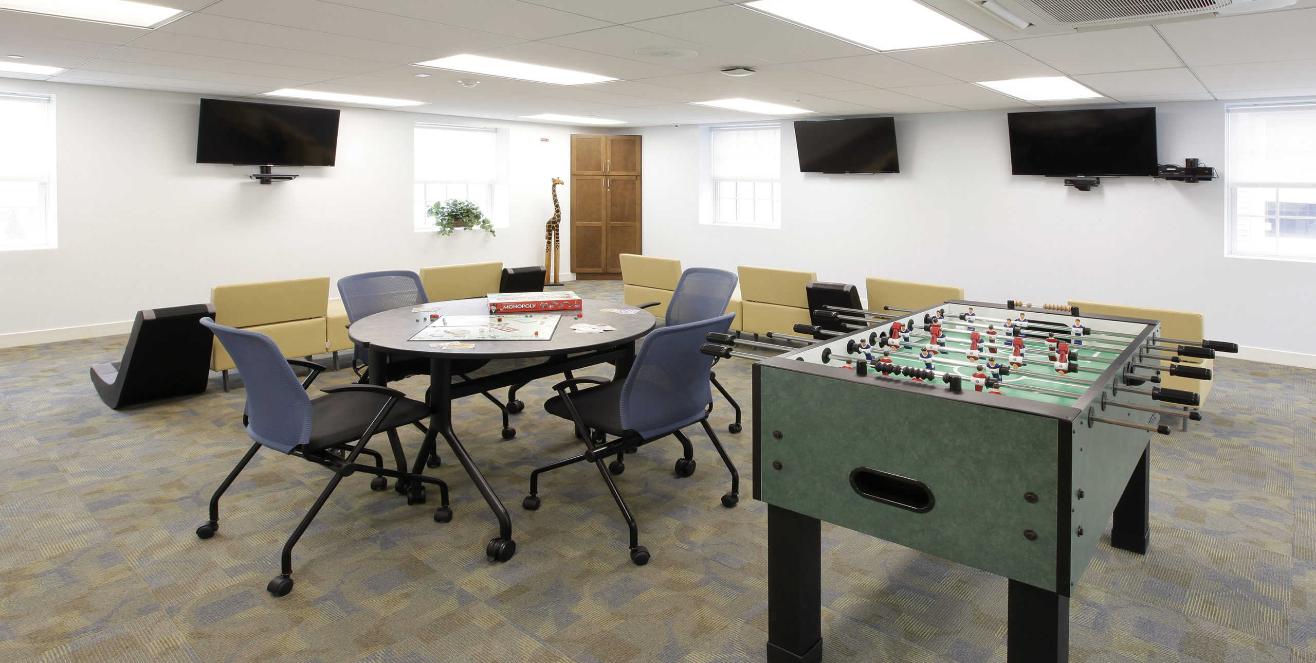 Recreation room with foosball and a table with chairs at The Family Center For Autism in Garden City