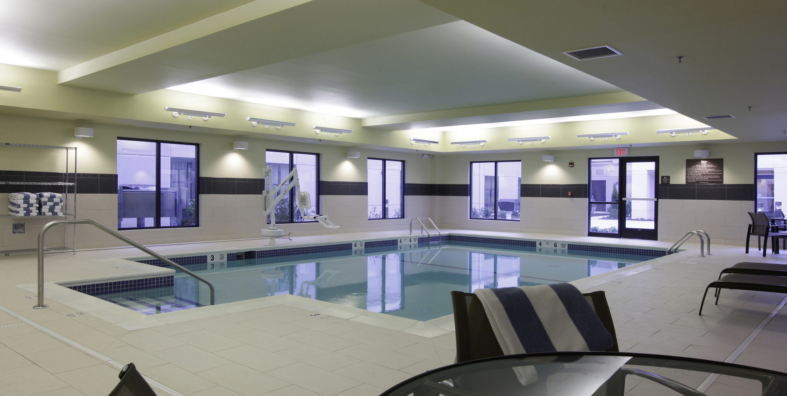 Indoor pool deck with lounge chairs at Homewood Suites in Carle Place