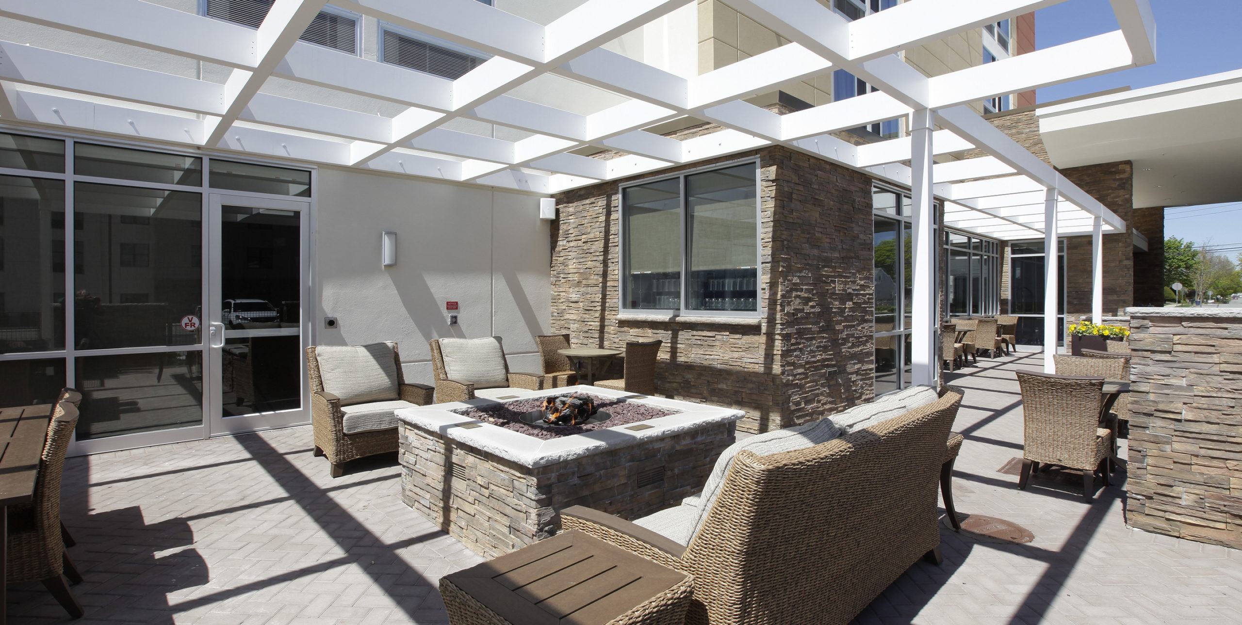 Outdoor seating around a fireplace at Spring Hill Suites by Marriott in Carle Place
