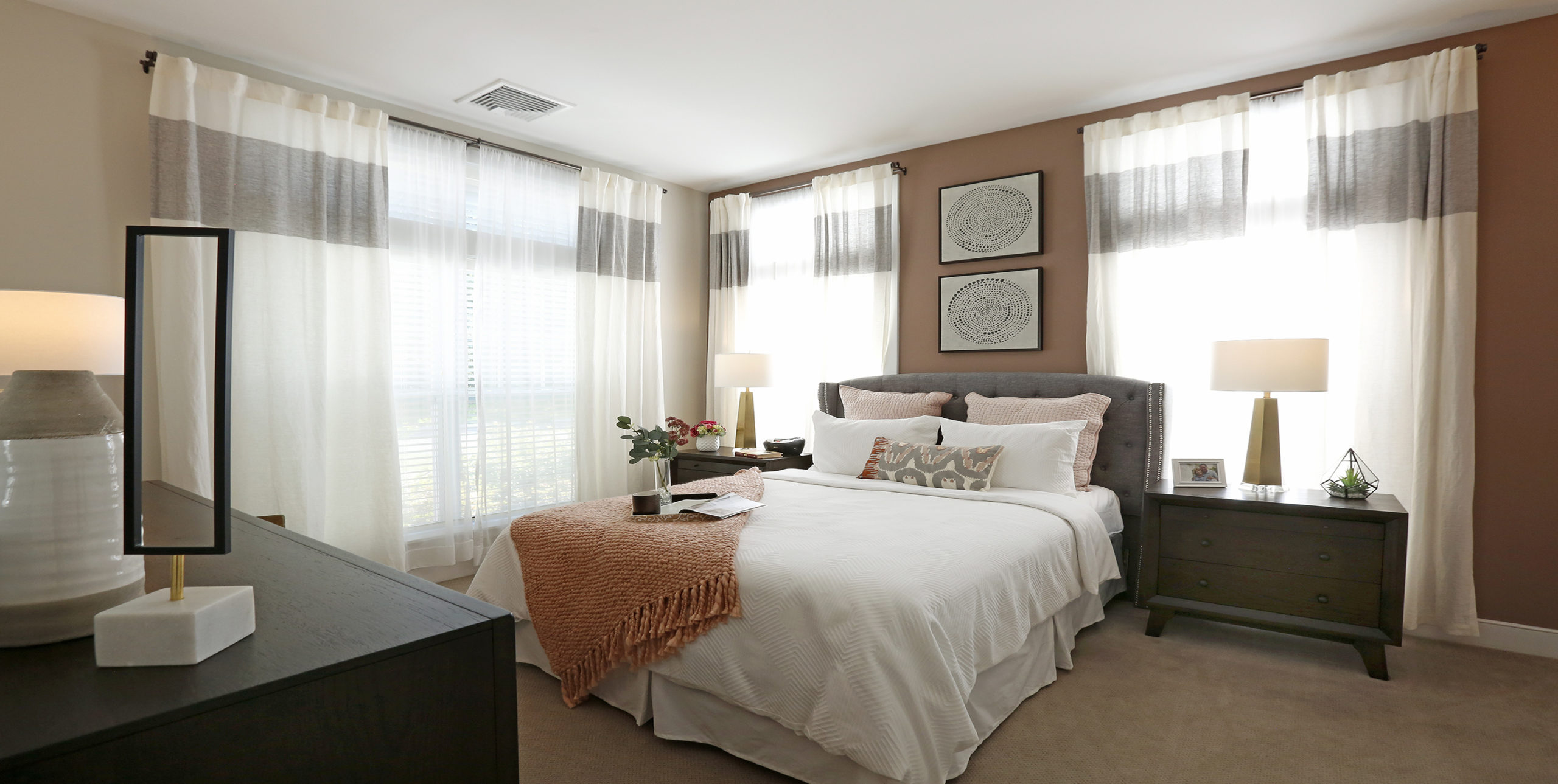 Bedroom showing a queen bed, table, and dresser in Brightview Senior Living in Sayville, NY