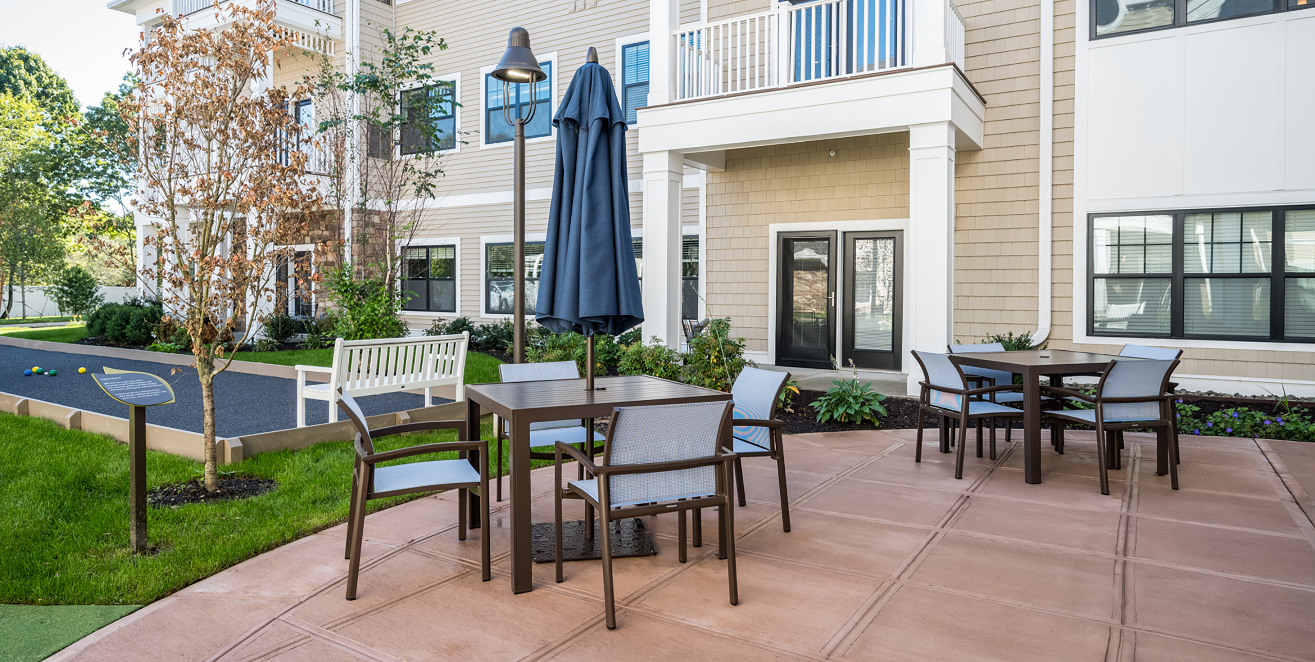 Outdoor common area with two tables and four chairs at each table at Brightview Senior Living Port Jeff