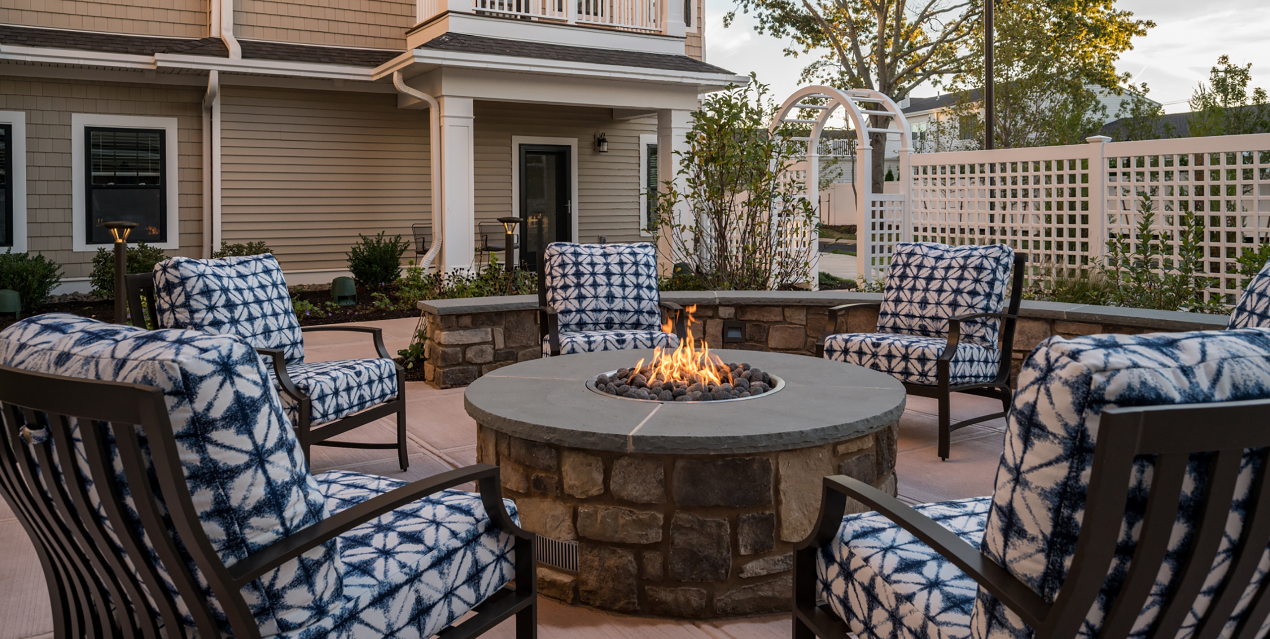 Chairs with cushions surrounding an outdoor fireplace at Brightview Senior Living Port Jeff