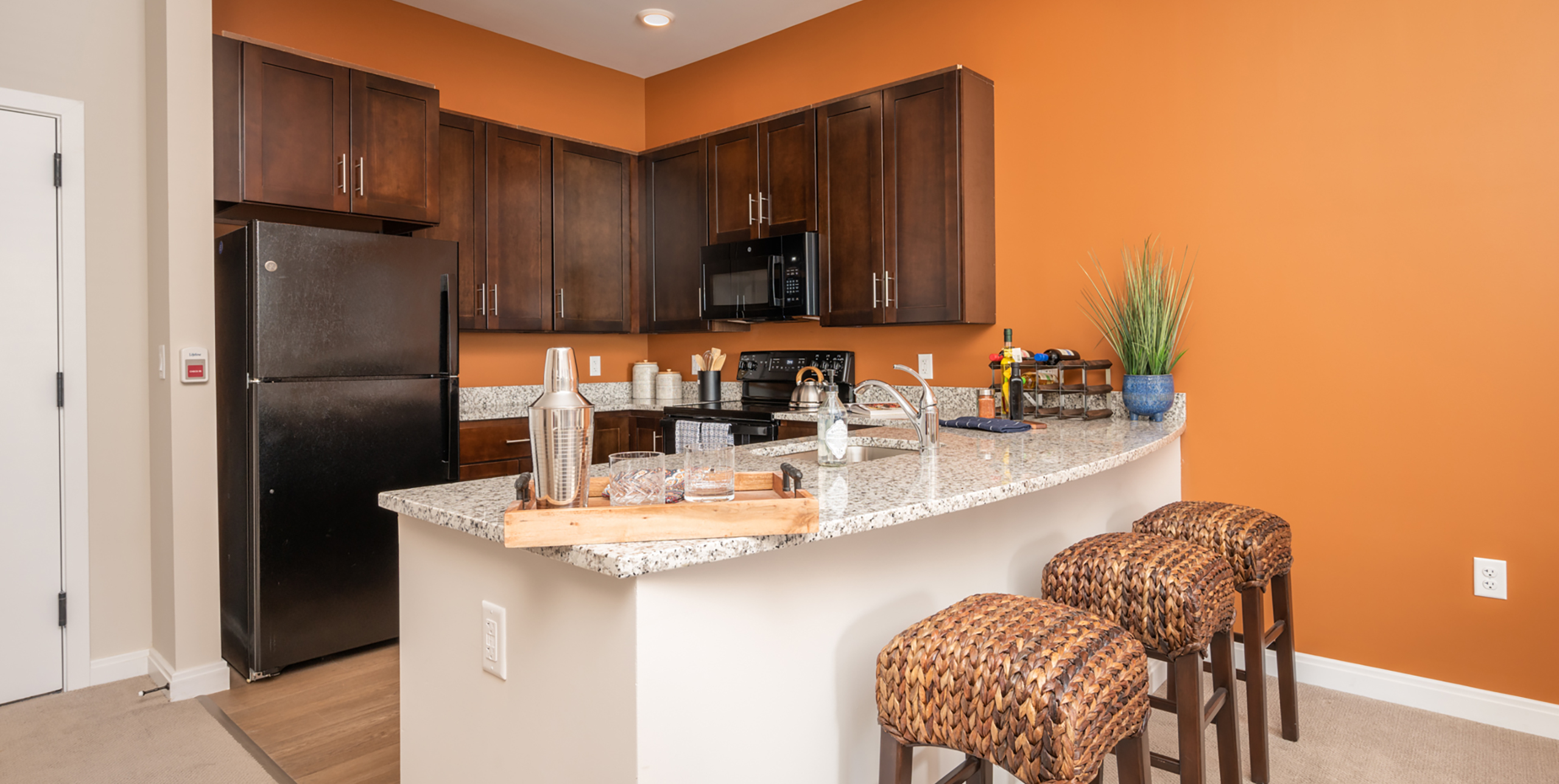 Kitchen inside of apartment with three stools against the counter at Brightview Senior Living Port Jeff