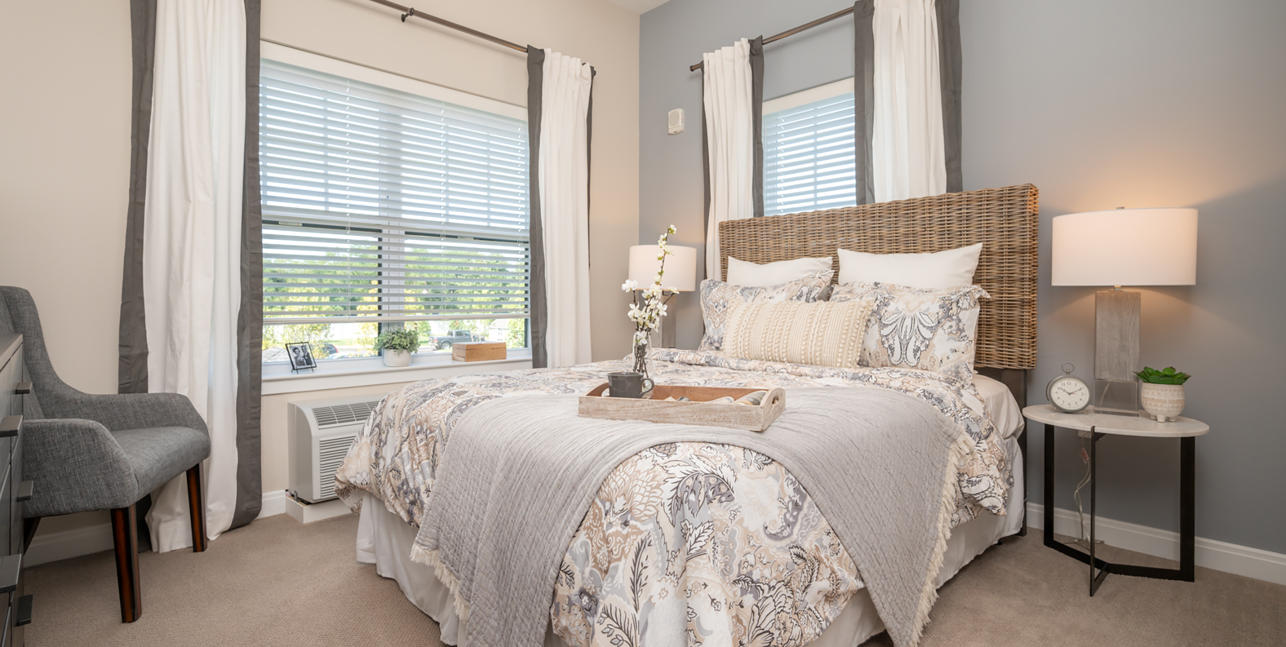 Queen sized bed with a night stand and small chair in a bedroom at Brightview Senior Living Port Jeff